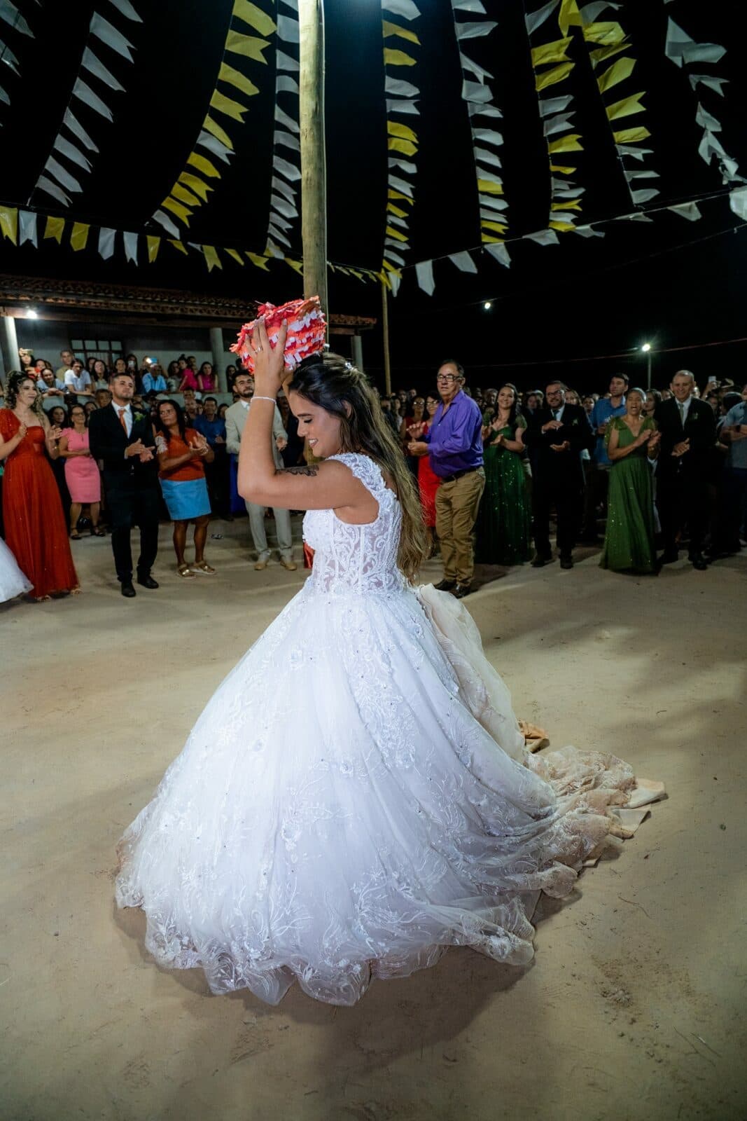 Noiva segurando um buquê durante a celebração, cercada por convidados.