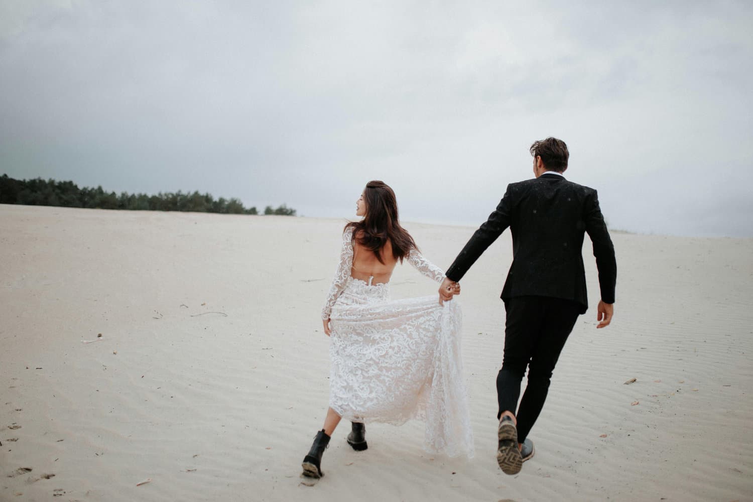 Casal de mãos dadas em um ensaio na praia, entre coqueiros.